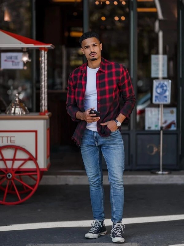 Man in Red and Black Plaid Dress Shirt and White Pants Standing Near the  White Wall  Free Stock Photo