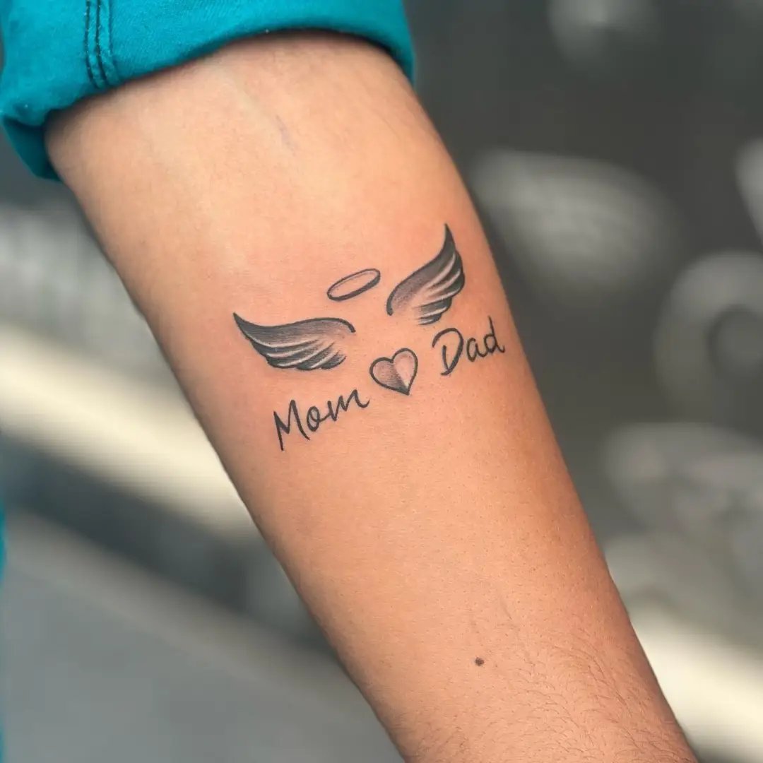 Mom dad with heart and wing tattoo on hand
