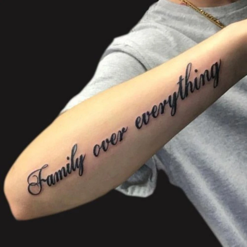 Text tattoo on hand - family over everything