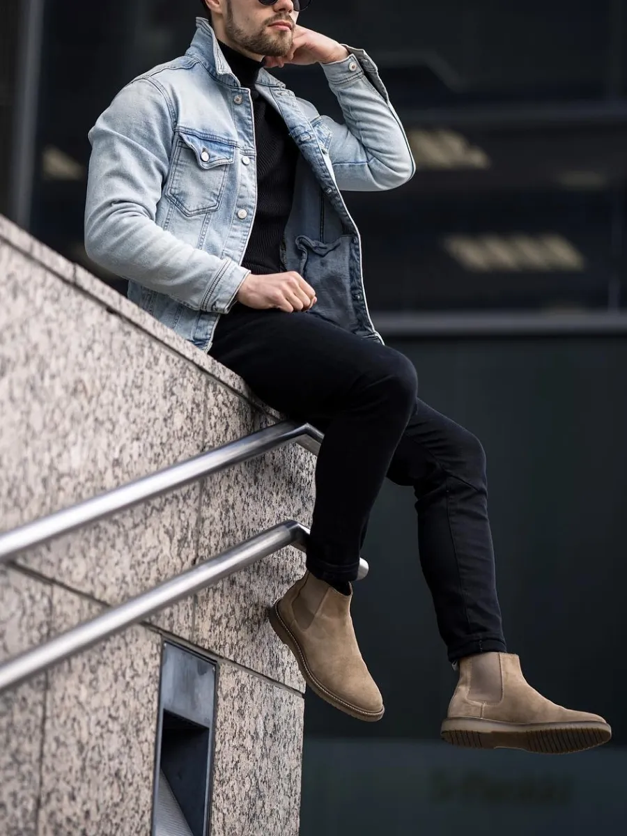 A man wearing black Turtleneck with blue denim jacket and black jeans